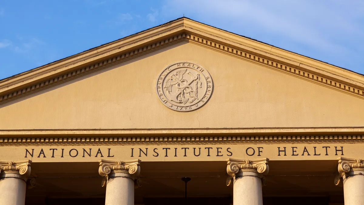 An entrance to a National Institutes of Health building is lit by the sun on a clear day.