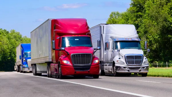 Horizontal shot of red, white, and blue trucks on an interstate with heat waves rising from the hot asphalt