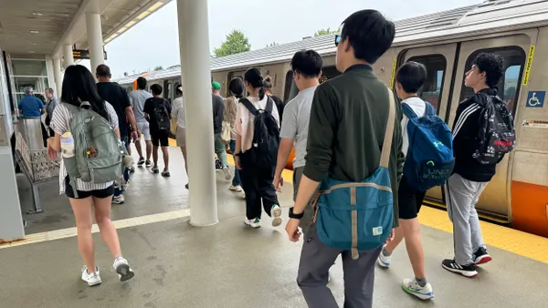 People on a station platform walking alongside a train.