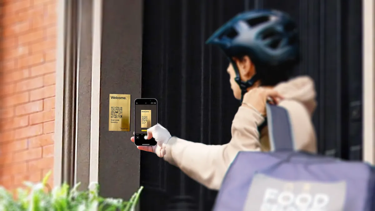 A person holds their phone in front of a metal plaque with a QR code on it.