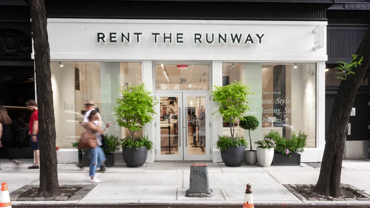 Tall trees flank a white Rent the Runway store in New York City, as smaller potted trees flank its doorway.