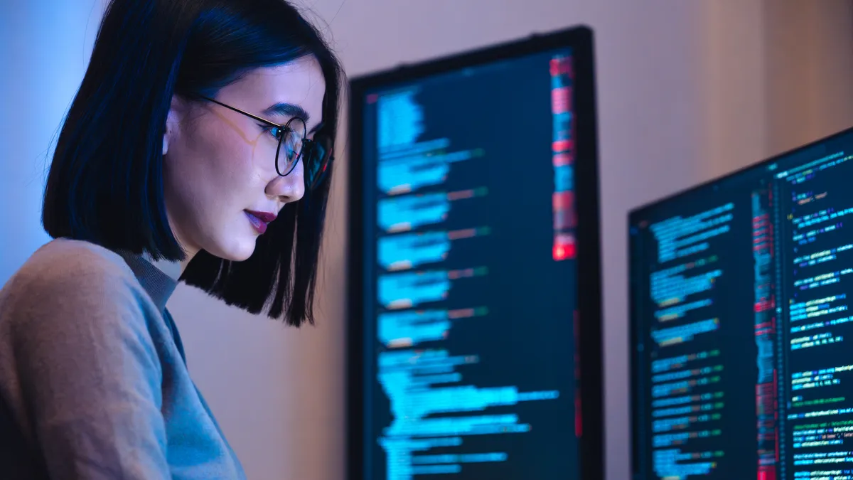 software developer working on coding computer screen and flowchart at night in modern office