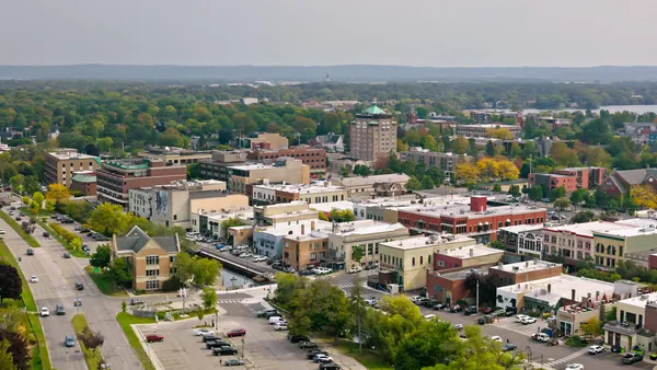 Aerial view of small city surrounded by green forest.