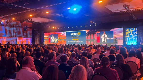 from the back of a ballroom, a crowd watches a keynote speaker. the screen says Scout AI
