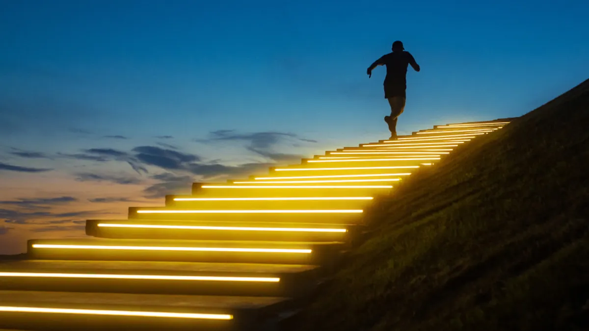 a man runs up a glowing staircase after sunset