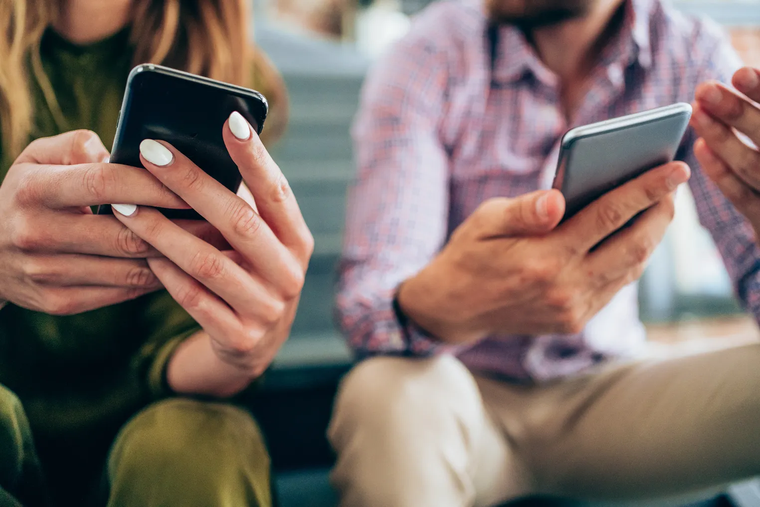 Young people sitting on the stairs and using smartphones.