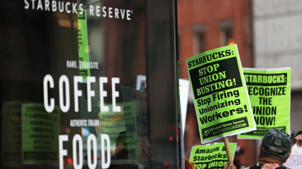 People hold signs while protesting in front of Starbucks on April 14, 2022 in New York City.