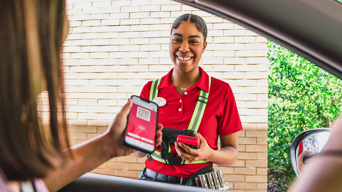 An image of a Chick-fil-A customer scanning her rewards program at the drive-thru