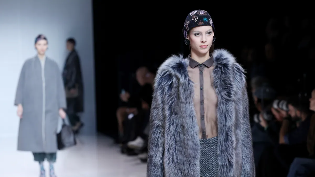 A model walks the runway wearing a fur coat.