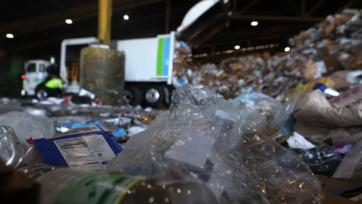 Piles of plastic packaging at a recycling facility, truck in the background