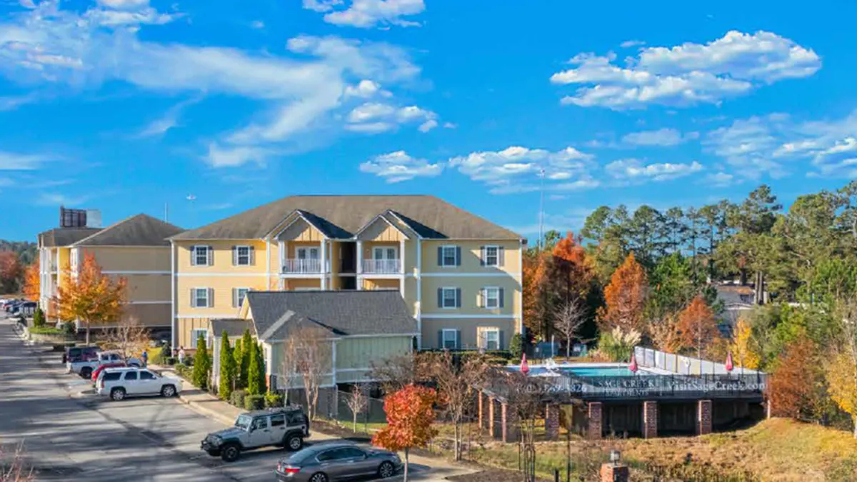 Three-story garden style apartments surrounded by pool, parking lot and trees