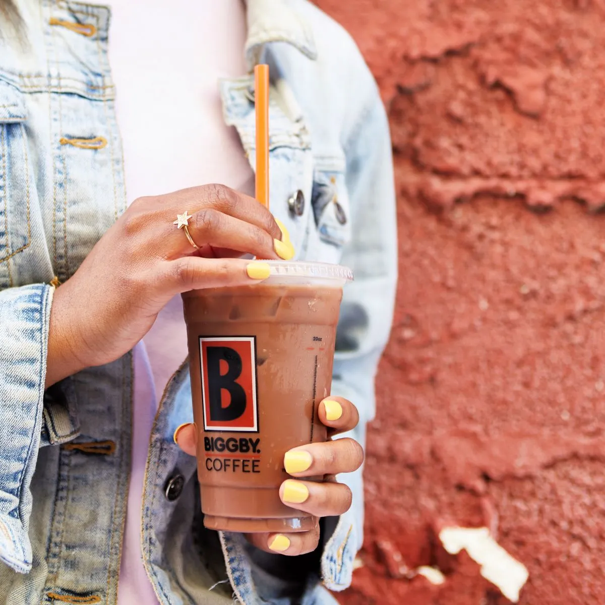 A hand of an African-American woman holding a Biggby iced coffee drink