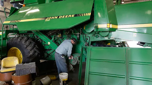 A man works on a giant green combine