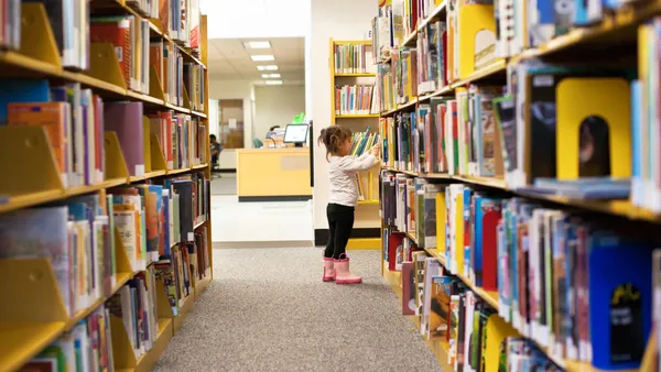 Girl wearing boots standing in between library shelves