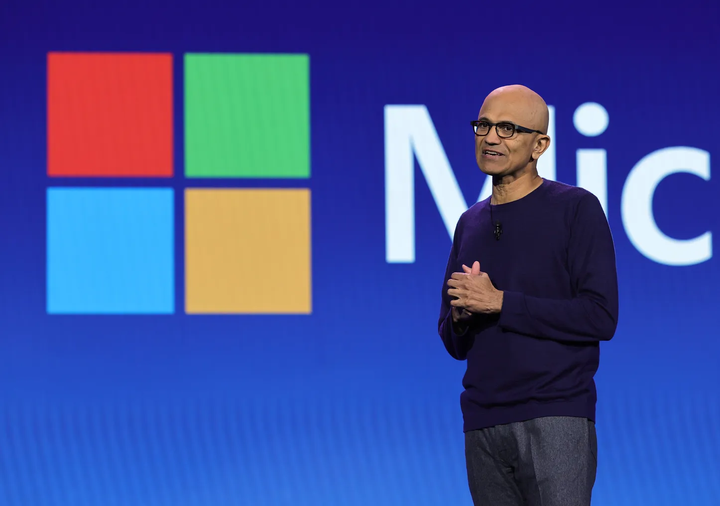 CEO Satya Nadella of Microsoft pictured on stage with the Microsoft logo in the background.