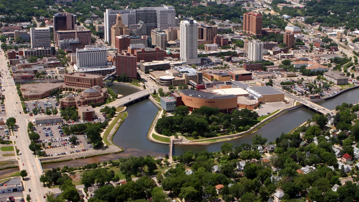 Aerial view of buildings surrounded by trees. The image also includes a waterway with several bridges.