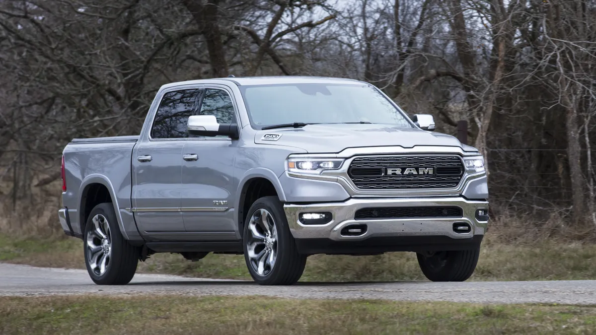 A silver 2021 Ram 1500 Limited pickup truck with trees in the background.