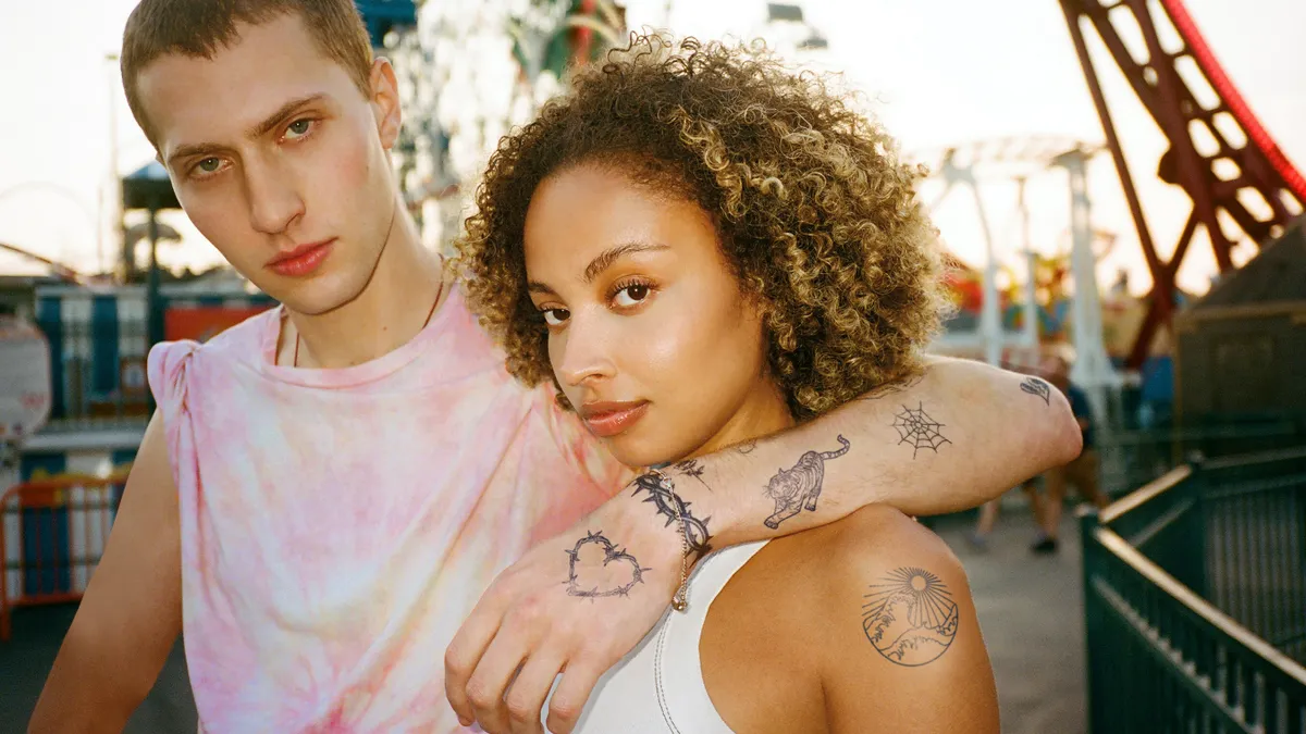 Two people with temporary tattoos on their arms stare directly into the camera.