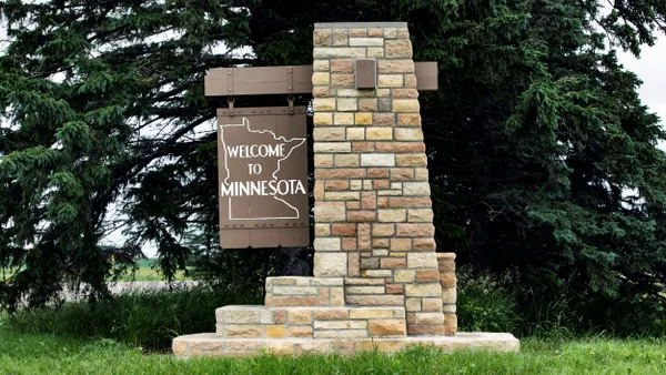 A sign made of brick and wood to welcome people to the state of Minnesota.