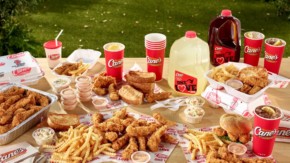 A bunch of chicken fingers, fries, toast slices, lemonade and iced tea on a picnic blanket.