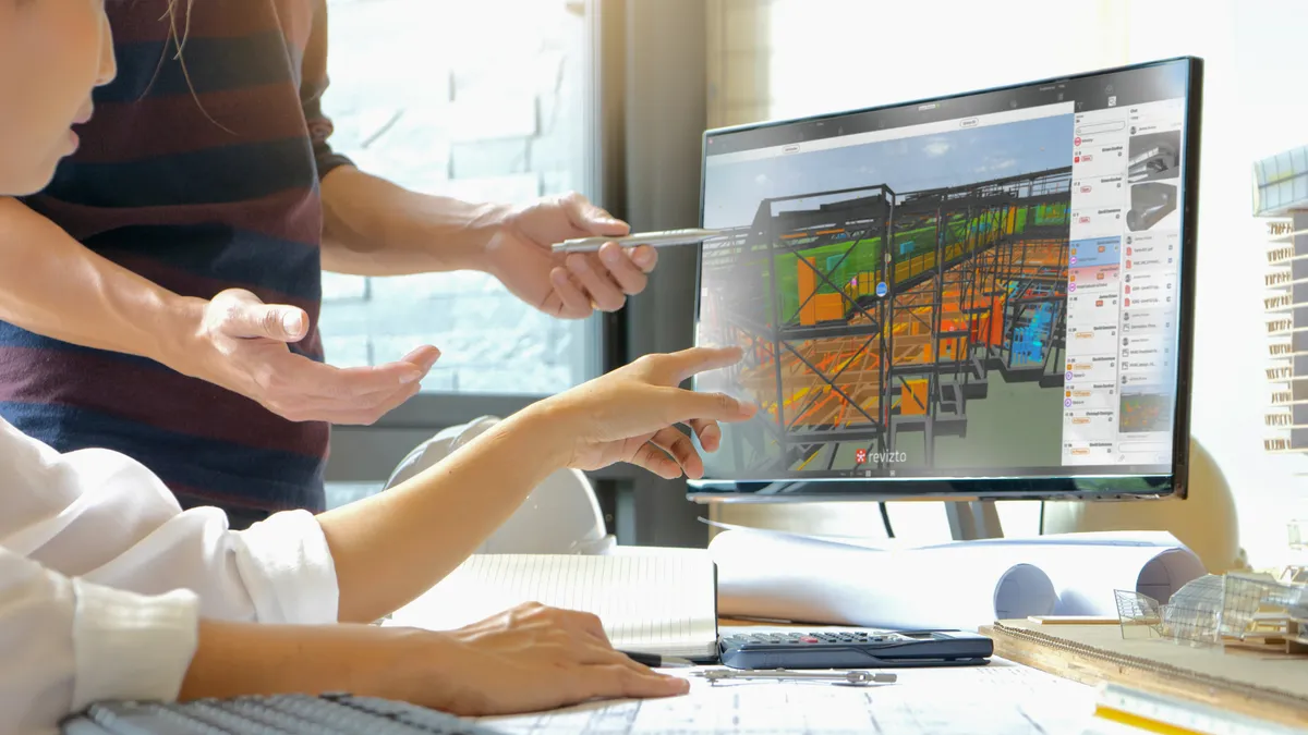 Two people looking at a Construction model graphic on a computer.