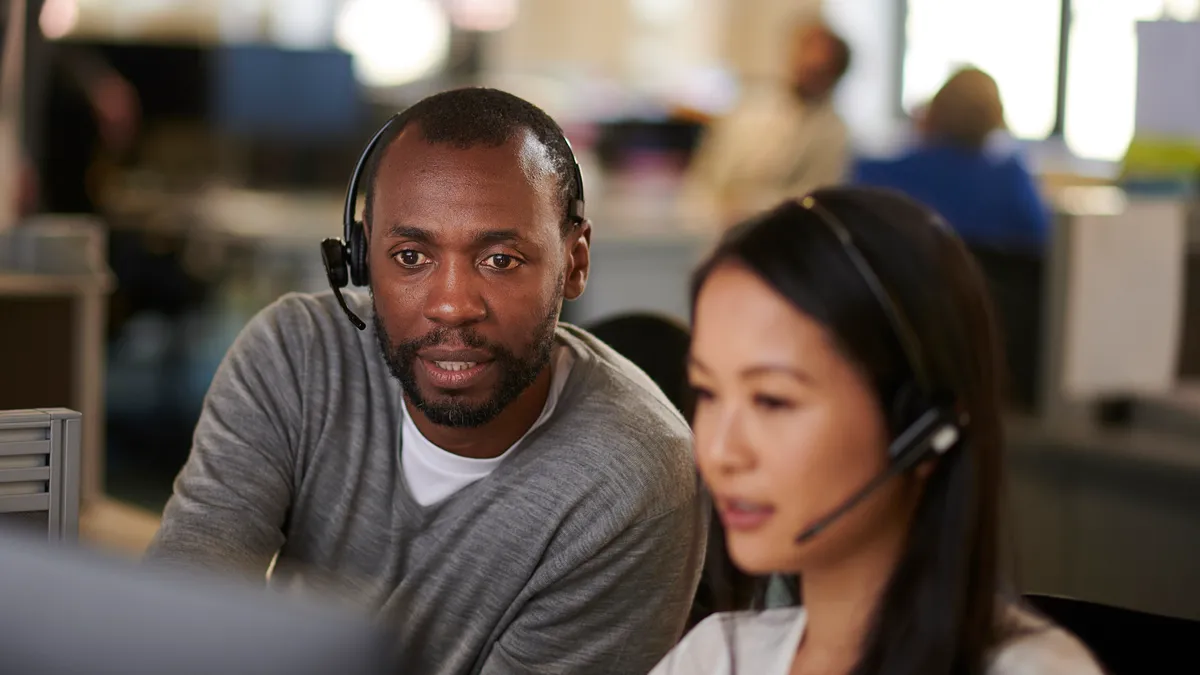 An employee aids his colleague in a call center.