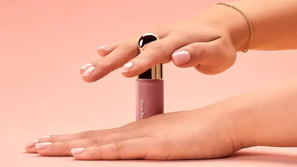 A person using two hands to unscrew Rare Beauty's Soft Pinch liquid blush