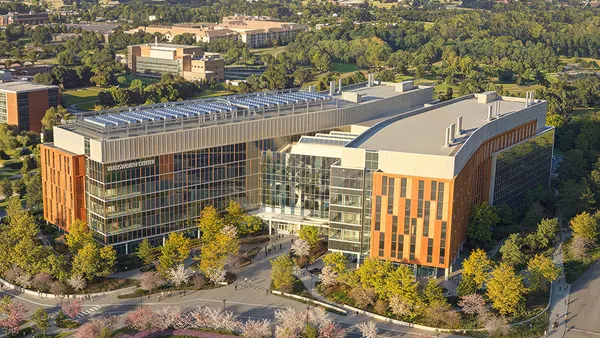 A rendering of a large, modern-looking building at sunset covered with windows and glass.