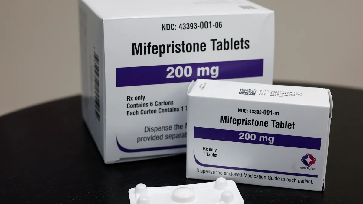 Mifepristone pills are seen on a table next to their packaging.