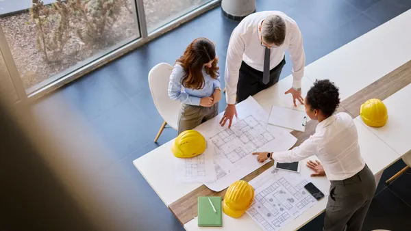 An aerial view of a group of people having a meeting over construction plans.