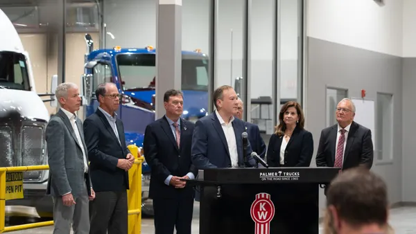 Officials gather at a dealership in Indiana around a podium.