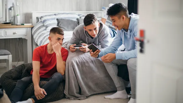 Three teens sit together while looking at a phone.