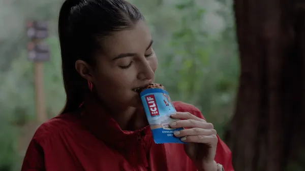 A woman bites a Clif Bar after a workout