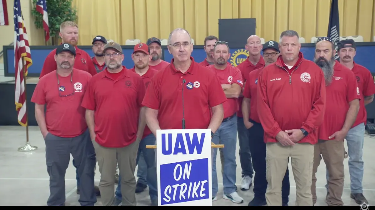 Fourteen people in red shirts, with one standing behind a podium.