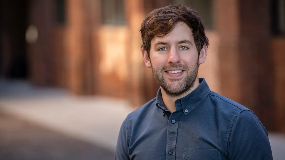A smiling man in a collared shirt poses for a photo