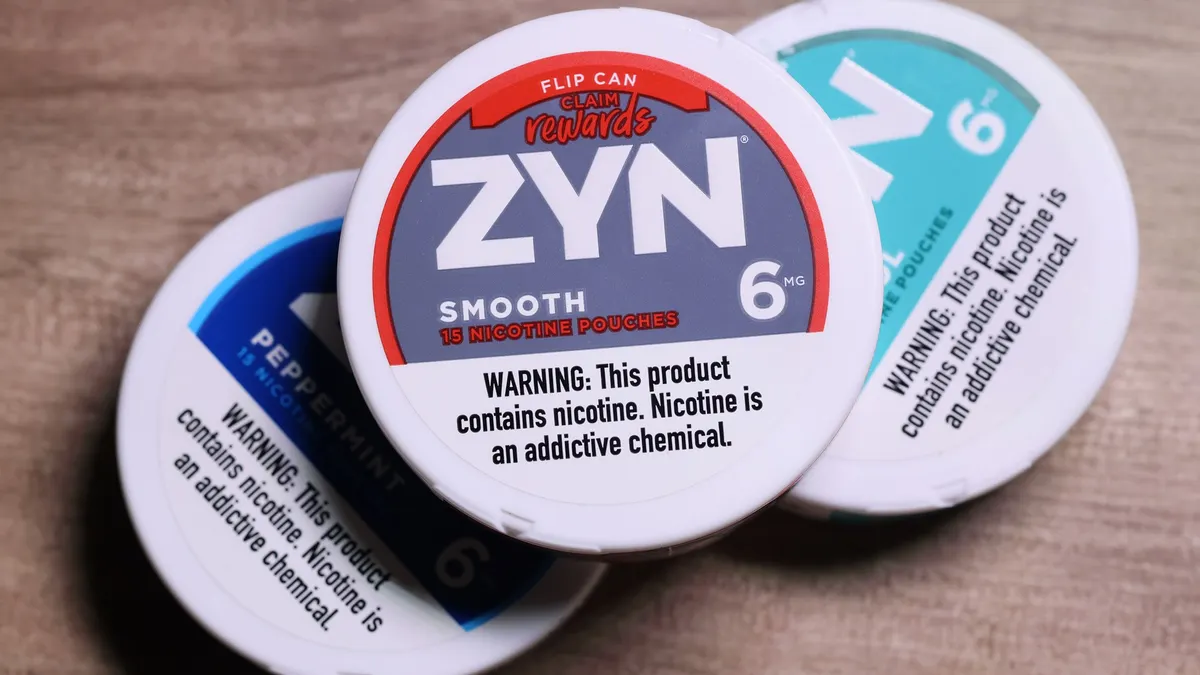 A photo of several containers of nicotine pouches. The top container says "Zyn smooth. Warning: This product contains nicotine. Nicotine is an addictive chemical."