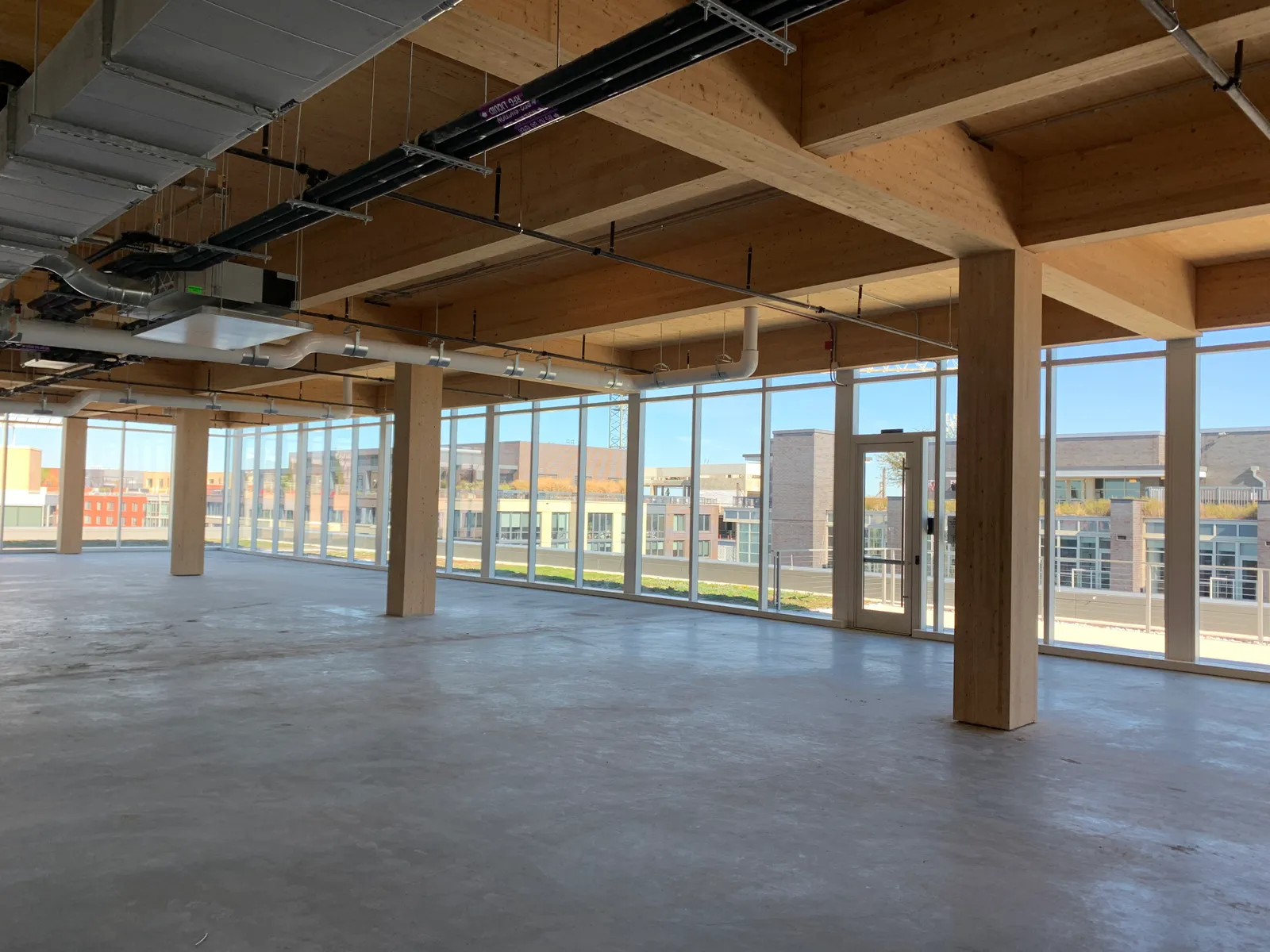 In an unoccupied floor of a mass timber overbuild, mass timber columns are prominent in the foreground.