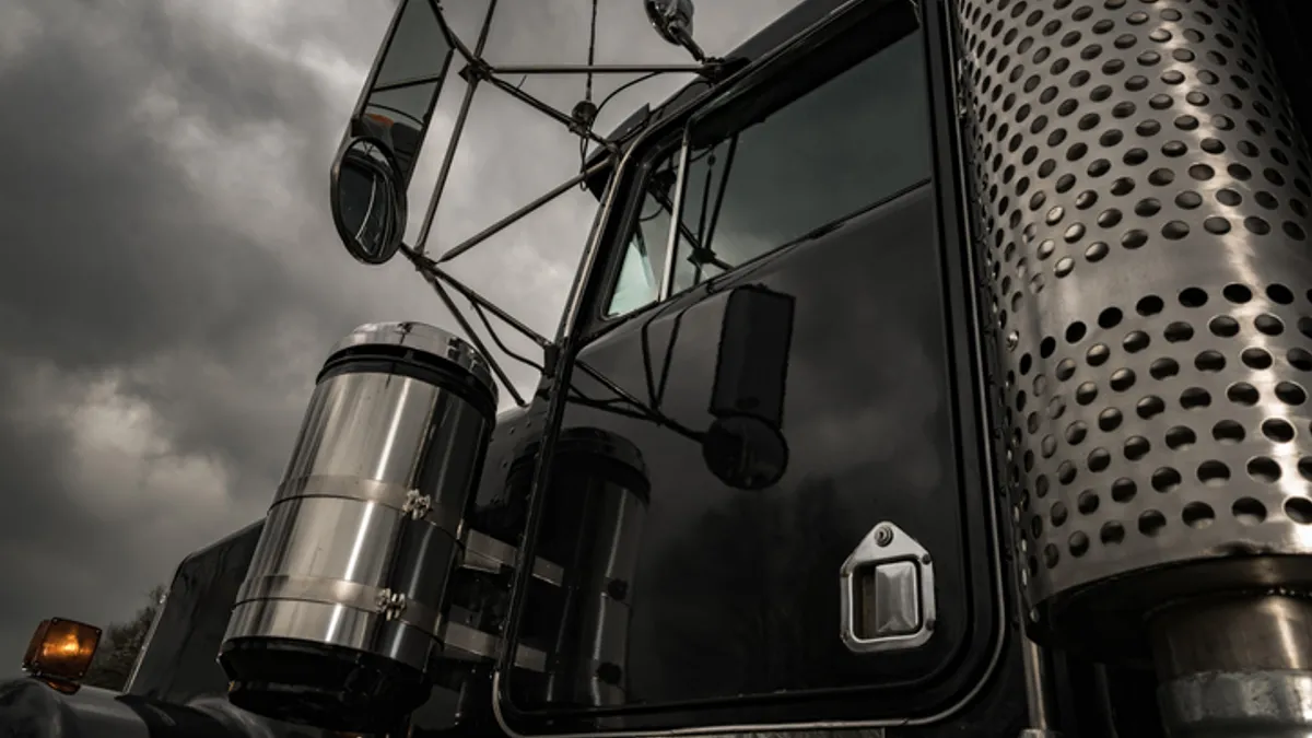 A black truck under a dark storm cloud.