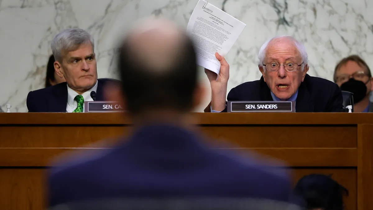 Senate Health, Education, Labor, and Pensions Committee Chairman Bernie Sanders waving a report as he questions Moderna CEO Stéphane Bancel at a March, 22, 2023 hearing.