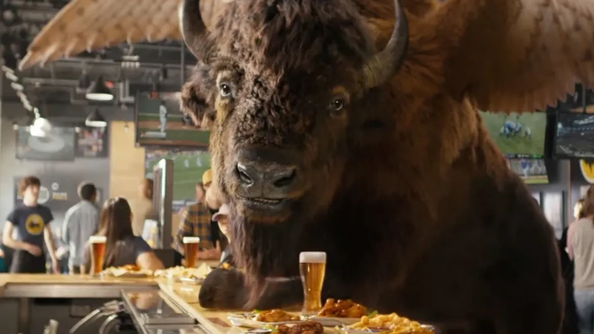 A CGI buffalo sits at a bar as part of a Buffalo Wild Wings campaign.