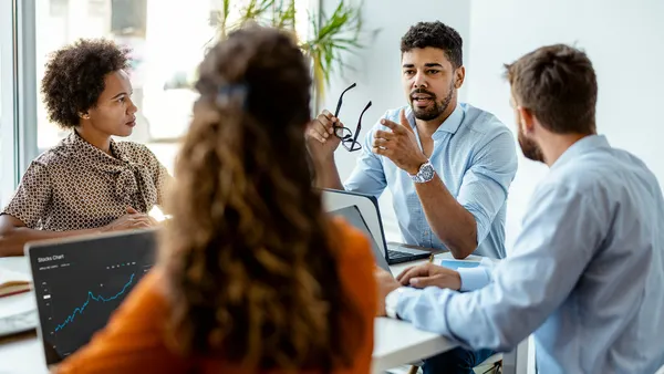 Confident and successful team. Group of young modern people in smart casual wear discussing business while sitting in the creative office