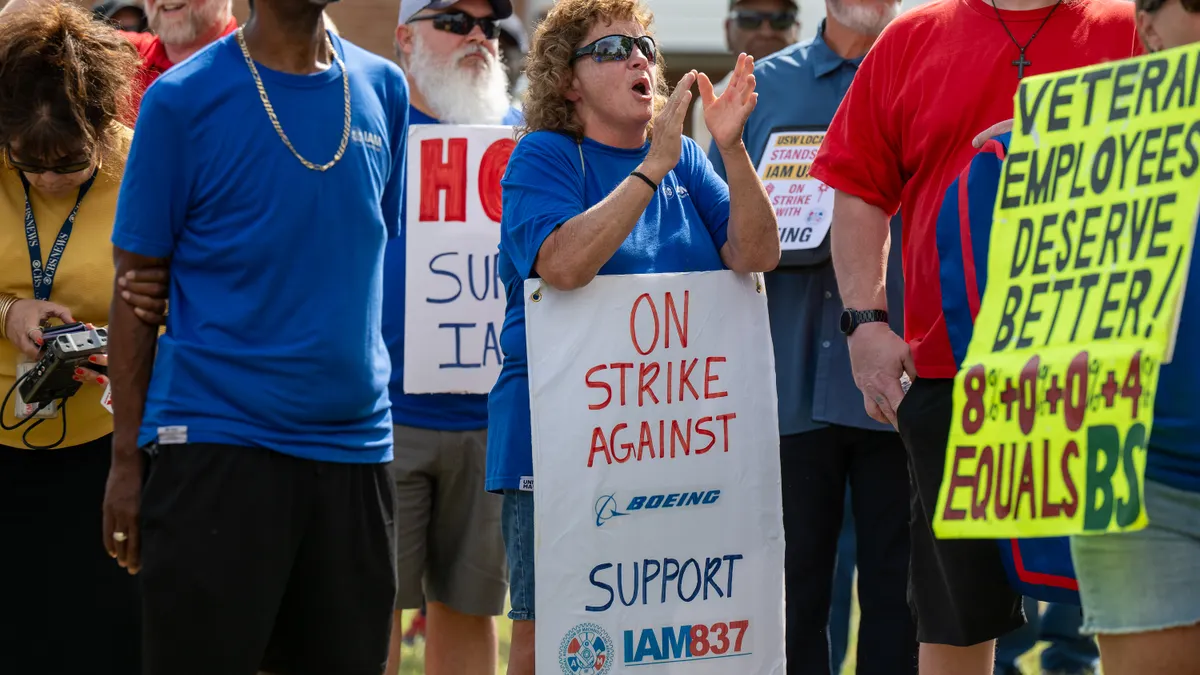 A group of people in blue shirts hold signs that say "Strike against Boeing."