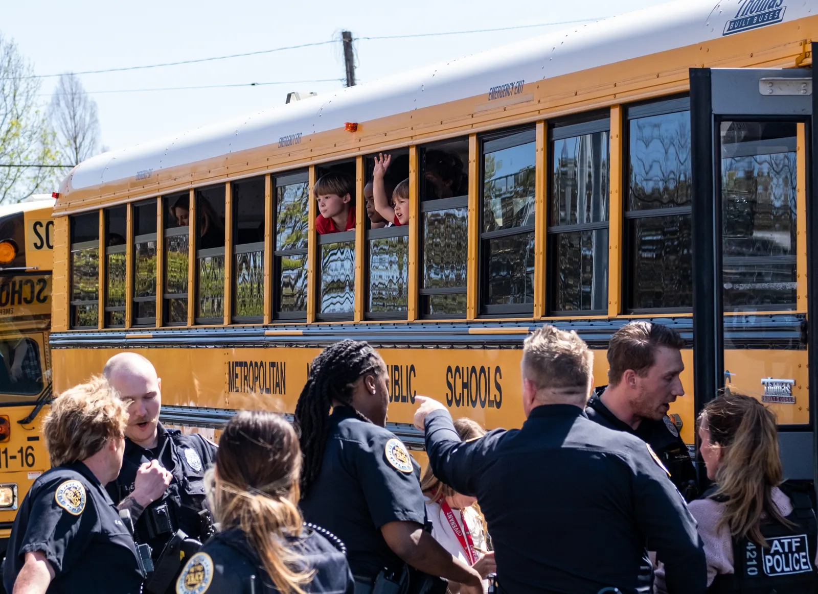 Children sit inside a bus looking out the window as police officers crowd around the bus doors