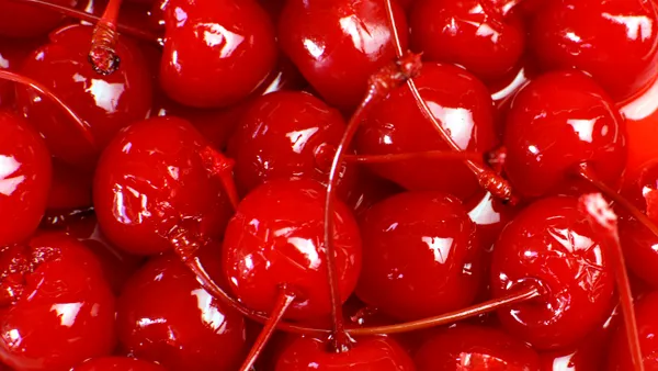 Several glossy maraschino cherries with stems