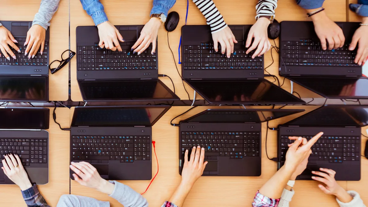 An aerial view of students using 8 different laptops side by side, while in school.