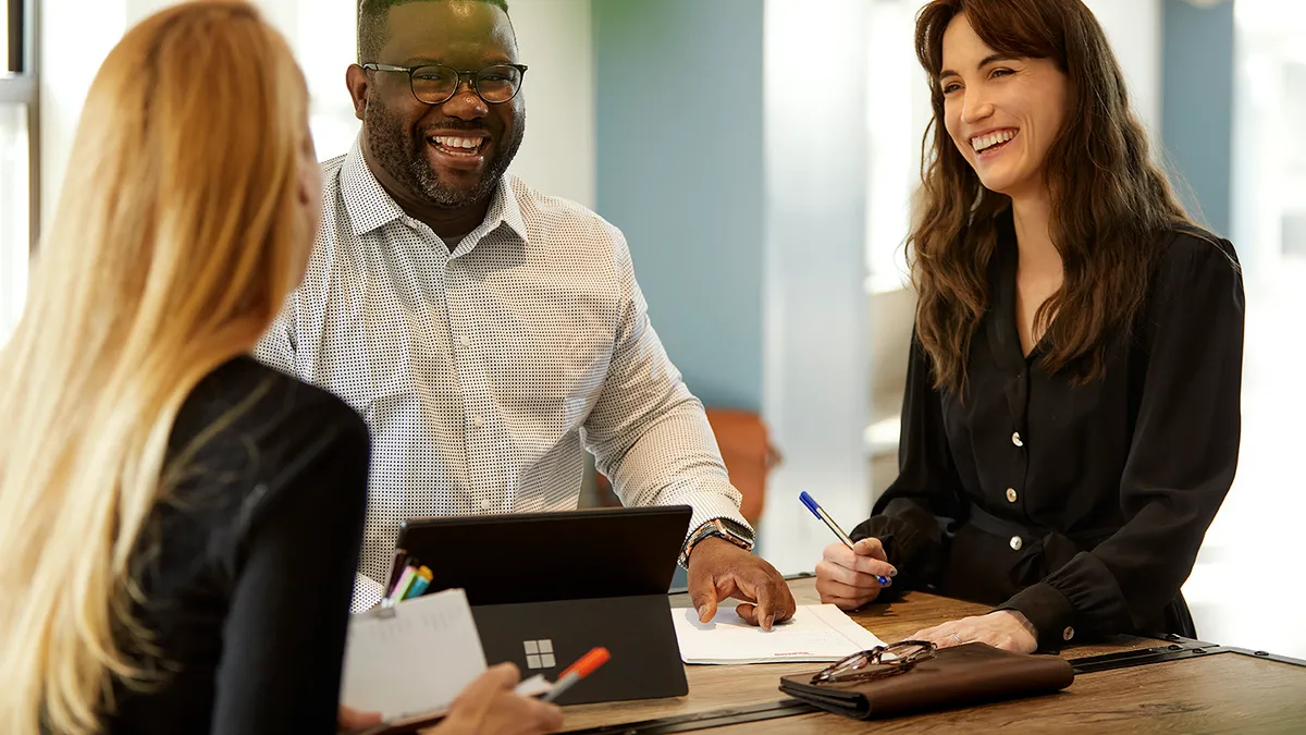 Three colleagues smiling while having a meeting