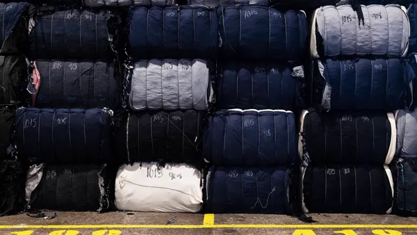 Textile waste is shown stacked on top of each other in a factory setting.