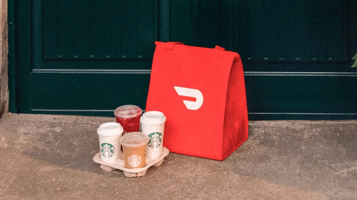 Several Starbucks beverages on a doorstep in front of a DoorDash delivery bag.