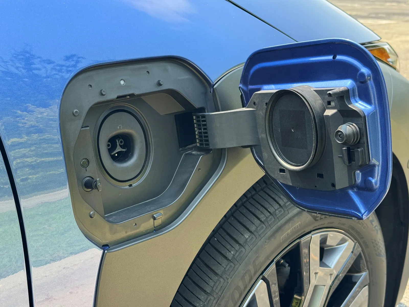 The flap to a charging port is open in a blue vehicle.