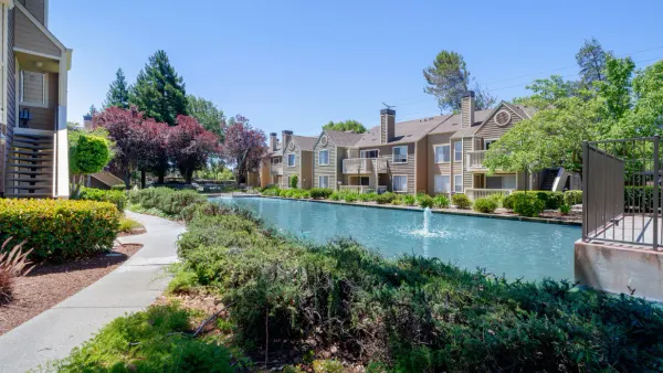 Tan, garden-style apartment property along a pond